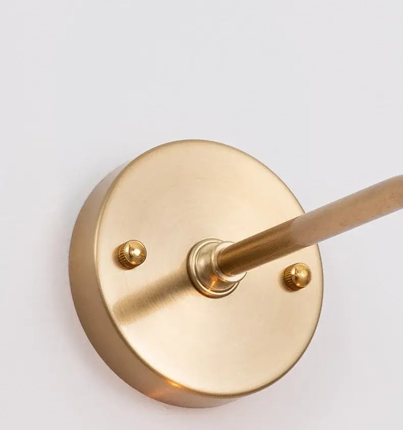 Modern brass wall lamp with decorbites amber glass featuring a sleek circular base and slender rod for living room decor