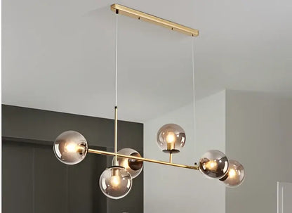 Modern brass and black art glass ball chandelier with six gold-toned glass globes for living room lighting