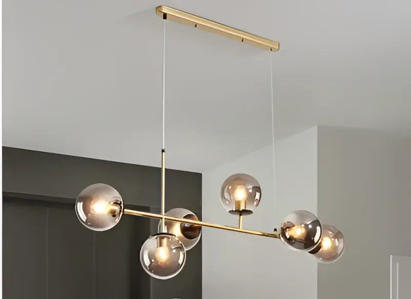 Modern brass and black art glass ball chandelier with six gold-toned glass globes for living room lighting