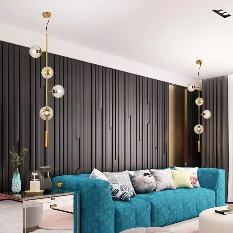 Modern brass and black art glass ball chandelier above teal velvet sofa with tufted cushions and decorative pillows