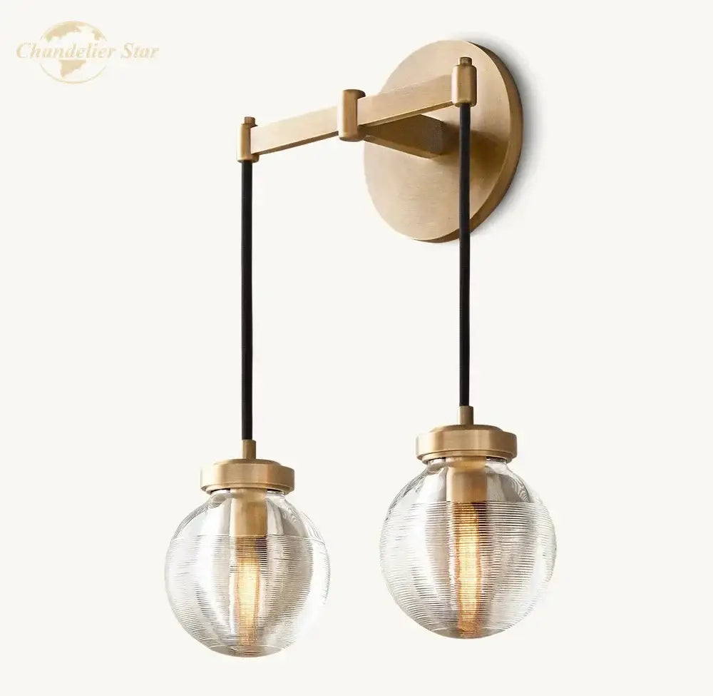 Modern brass and black crystal led wall sconce with two textured glass globes suspended by black cords for bedroom lighting