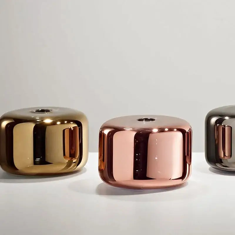 Polished metallic cylindrical vases in gold rose gold and dark bronze complement modern brass and black cylindrical glass pendant light decorbites cylindrical glass