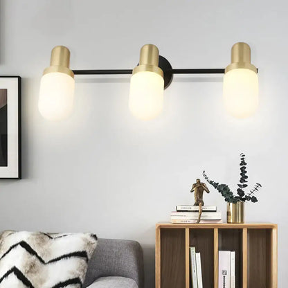 Modern brass and black glass sconce light with three frosted glass shades for bedroom wall lighting