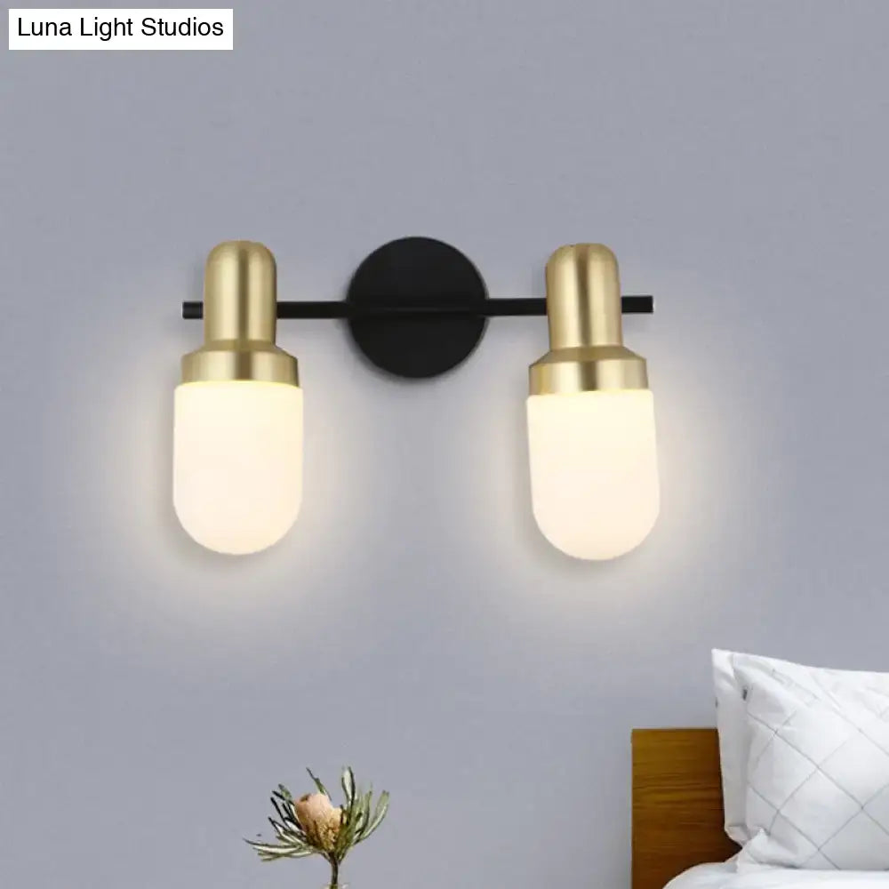 Modern brass and black glass sconce light with brushed brass fixtures and frosted glass shades for bedroom walls