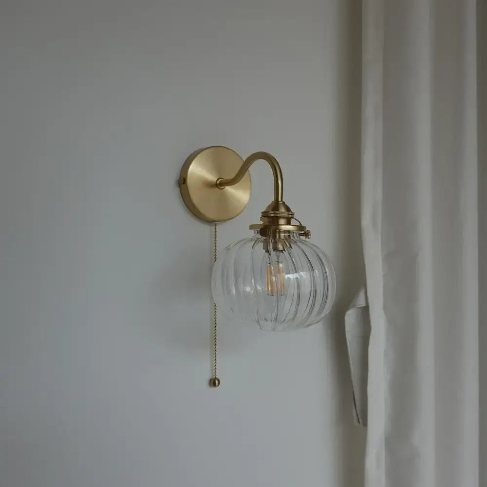Modern brass wall sconce with ribbed blue glass ball globe and pull-chain switch ideal for bedroom lighting
