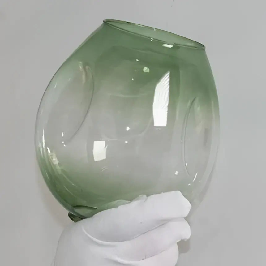 A translucent green glass bowl with embossed patterns complements modern brass and blue glass iron ball chandeliers
