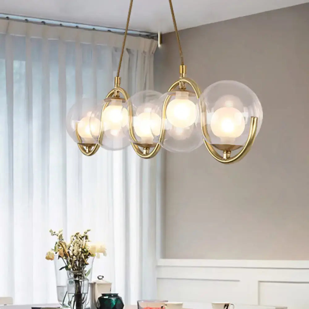 Modern brass and clear glass globe pendant light with five shades featuring adjustable chain cord length and fixture width