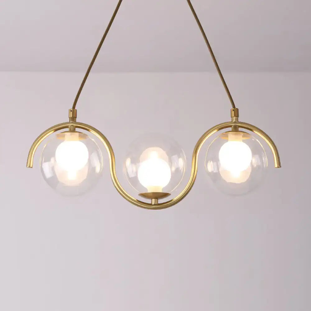 Modern brass and clear glass globe pendant light with three clear glass shades and adjustable chain cord length fixture width