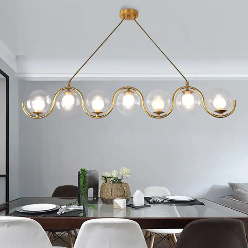 Modern brass and clear glass globe pendant light kitchen fixture with gold-toned metal arms and adjustable chain cord length