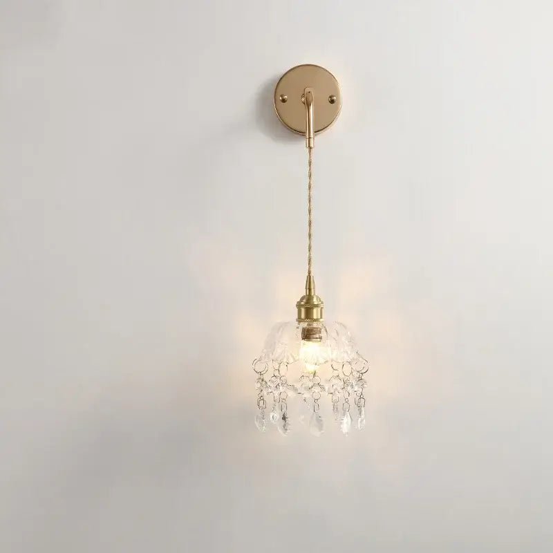 A modern brass wall lamp with clear glass shade and crystal droplets perfect for elegant bedroom decorbites clear glass