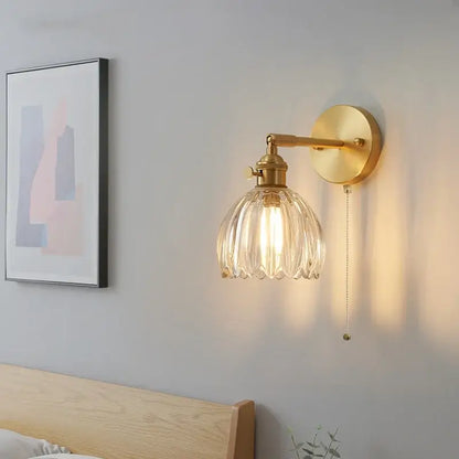 Gold-finished modern brass wall light with faceted clear glass shade and pull chain for bedroom decorbites clear glass design