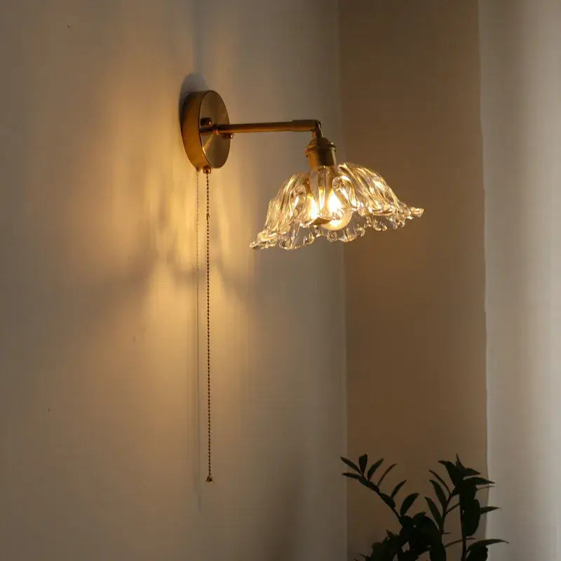 Modern brass and crystal led wall lamps featuring a delicate flower-shaped hand-blown glass shade with warm glow