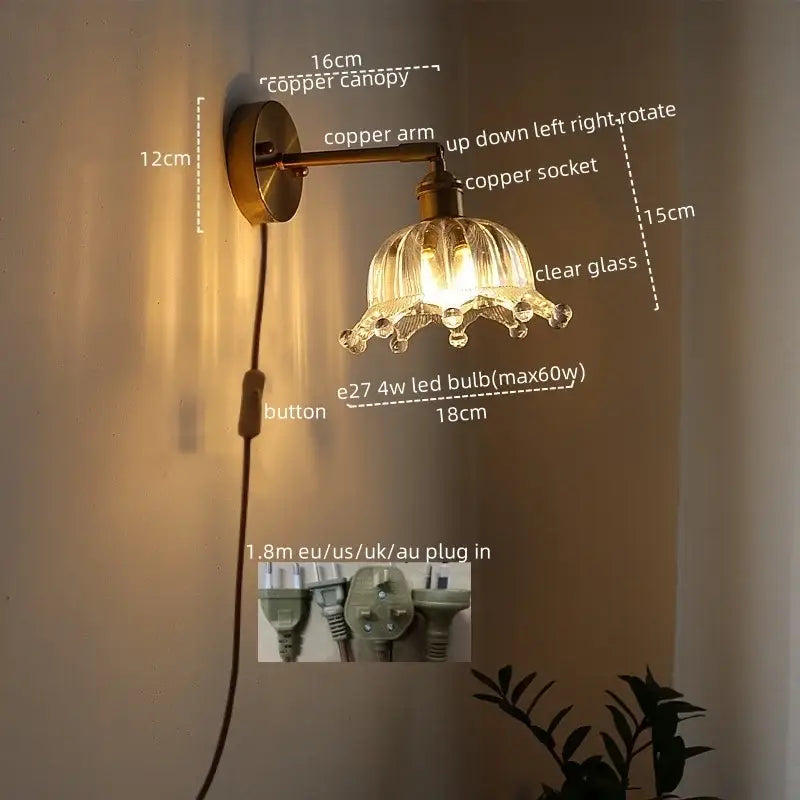 Modern brass and crystal led wall lamps feature a copper-finished arm and clear glass flower shade with crystal accents