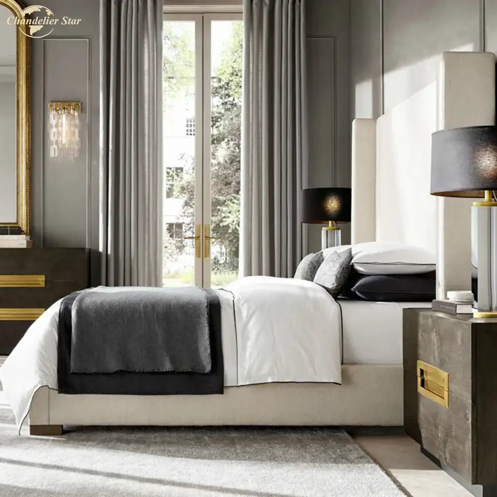 A modern brass and crystal wall sconce above a beige upholstered bed with white bedding and a dark gray throw, decorbites crystal wall
