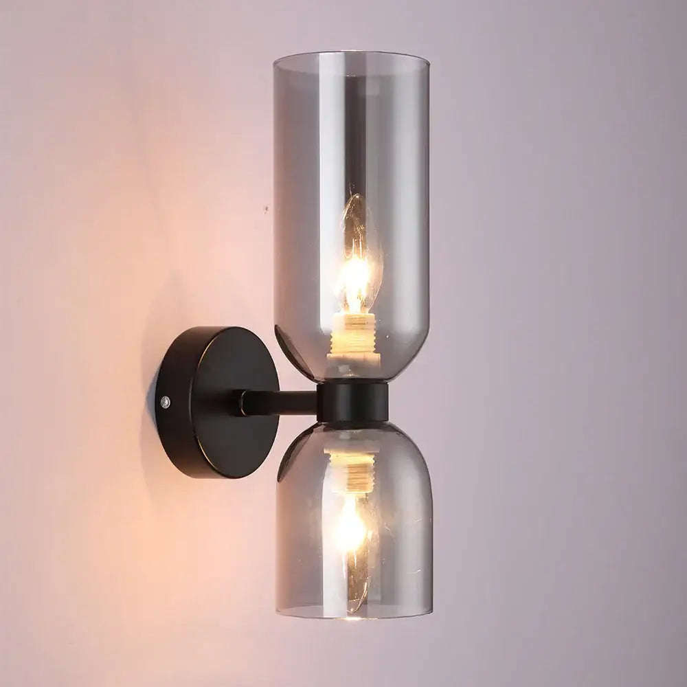 Modern black metal wall lamp with two smoked decorbites glass ball shades and exposed filament bulbs for bedroom use