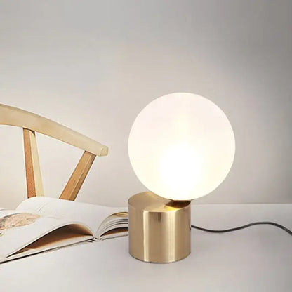 Modern brass and decorbites glass circular table lamp with frosted globe and soft lighting for bedroom use