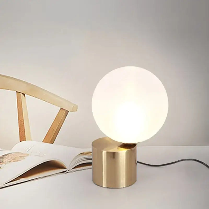 Modern brass and decorbites glass circular table lamp with frosted globe and soft lighting for bedroom use