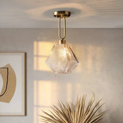 A clear faceted diamond glass pendant lamp with brass-finished metal fixture for modern living room lighting