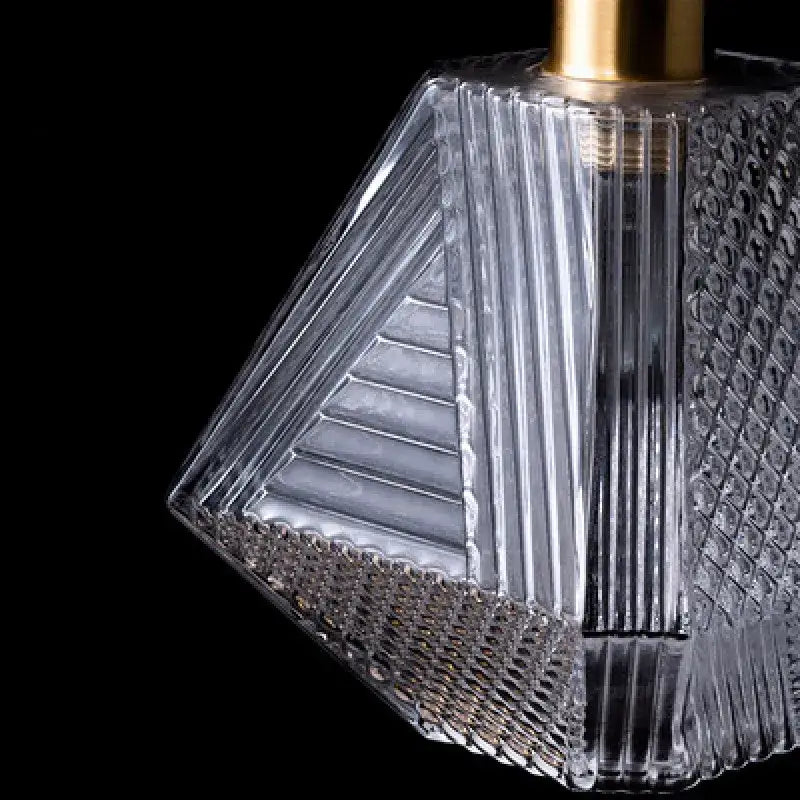 Modern brass and diamond glass pendant lamp featuring a clear geometric glass pendant lamp with gold-toned metal top