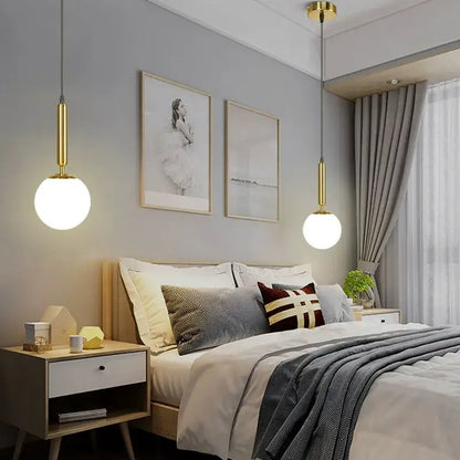 Modern brass and frosted glass ball pendant light with gold finish and spherical shades hanging above bed decorbites glass ball