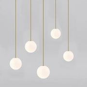 Five modern brass and frosted glass ball pendant lights hanging on slender rods for kitchen lighting decorbites glass ball pendant