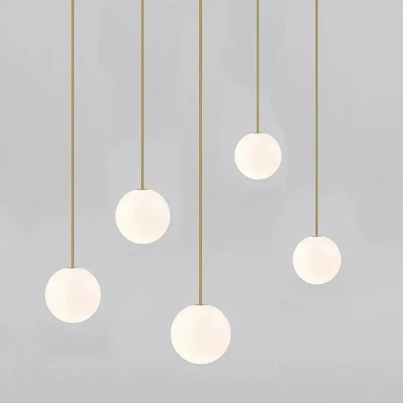 Five modern brass and frosted glass ball pendant lights hanging on slender rods for kitchen lighting decorbites glass ball pendant
