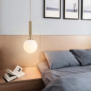 Modern brass and frosted glass pendant light with cylindrical stem and globe shade for dining room chandelier pendant light