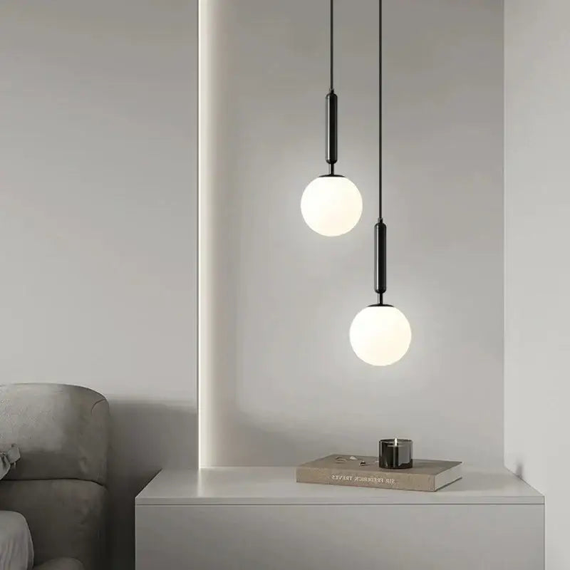 Two matte black glass chandelier pendant lights with frosted white spherical shades for modern dining rooms