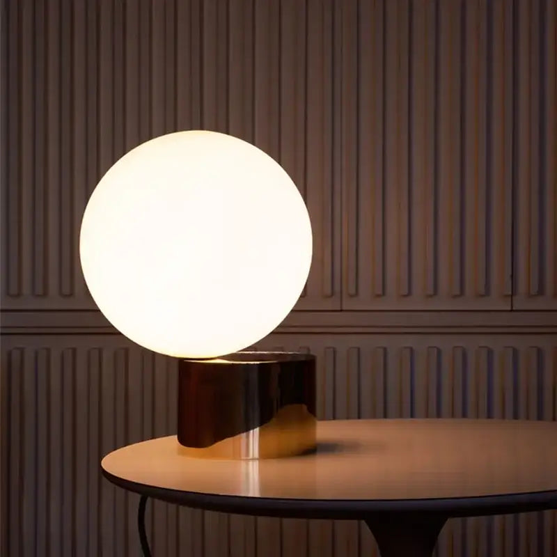 Modern brass and glass ball table lamp with a matte white glass globe on polished brass base for bedside decorbites glass ball