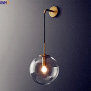 A sleek modern brass and glass ball wall lamp with a clear globe and black cord for bathroom decorbites glass ball