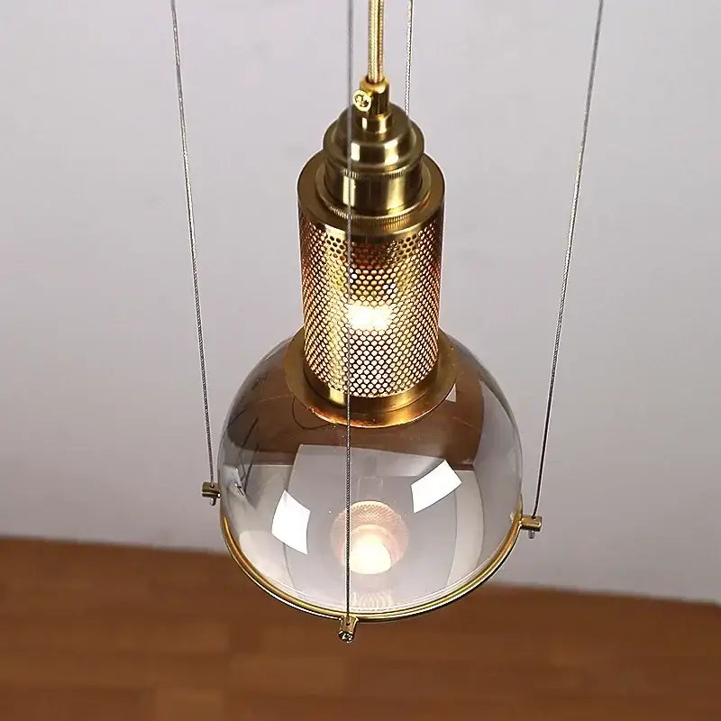 Modern brass and glass crystal ball led pendant light with gold-toned industrial design and perforated metal shade