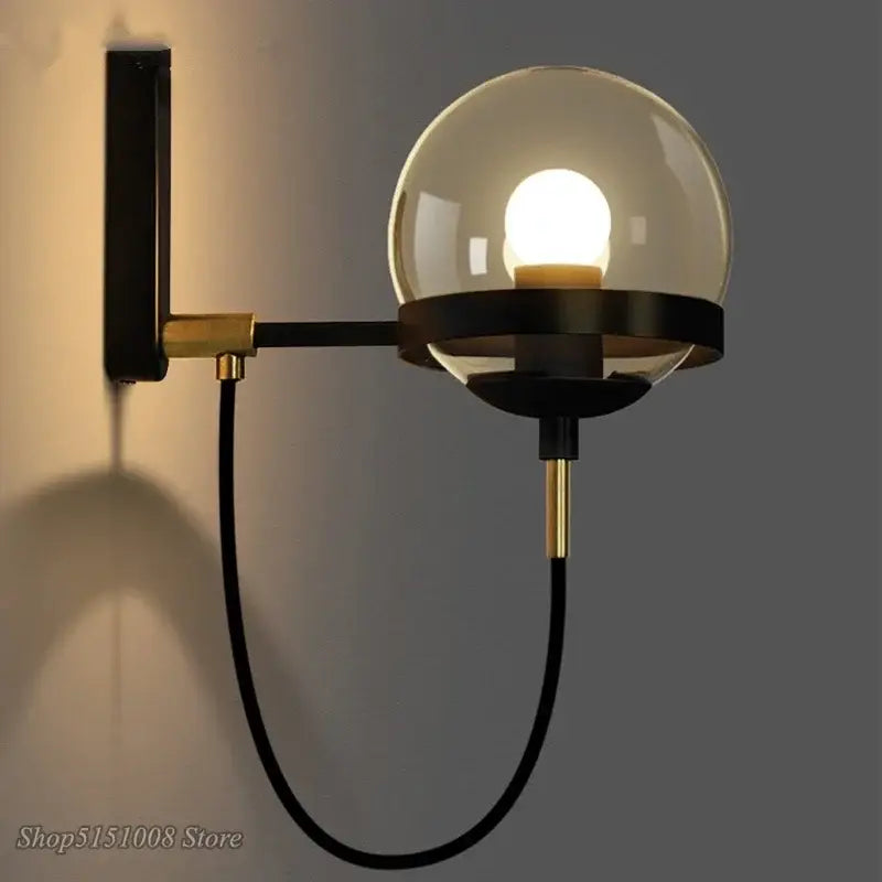 Modern brass and glass globe led wall lamp with black metal frame and spherical glass globe for bedroom use