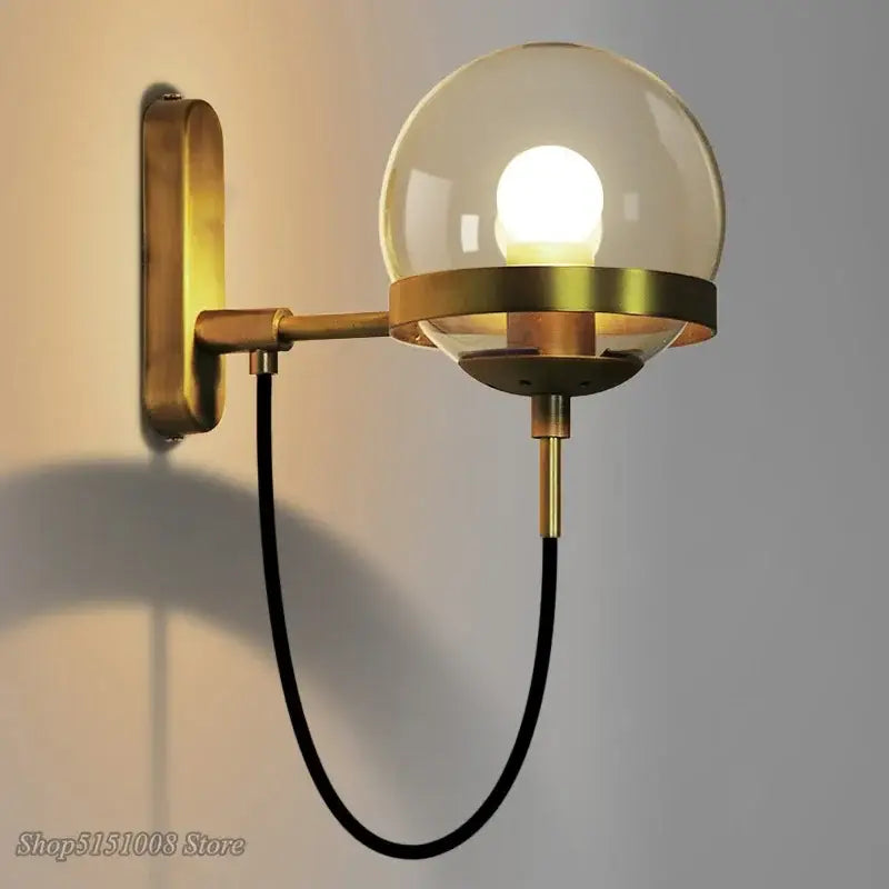 Modern brass and glass globe led wall lamp with spherical glass globe and black cord for bedroom lighting