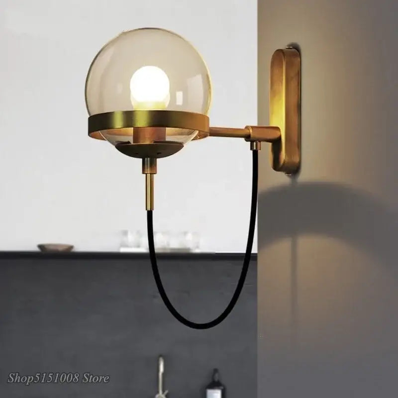 Modern brass and glass globe led wall lamps with spherical glass globe and black cord for bedroom lighting