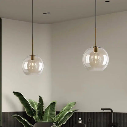 Two spherical glass pendant lights with brass fixtures and iron finish for cord pendant installation in dining room