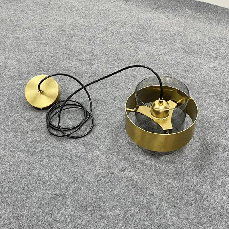Modern brass and glass pendant light with clear glass shade and black cord for kitchen or dining room lighting