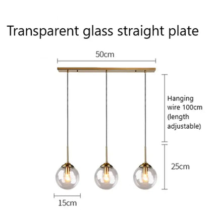 Modern brass and glass pendant lights with three clear glass pendant globes suspended from a wooden plate for kitchen dining room