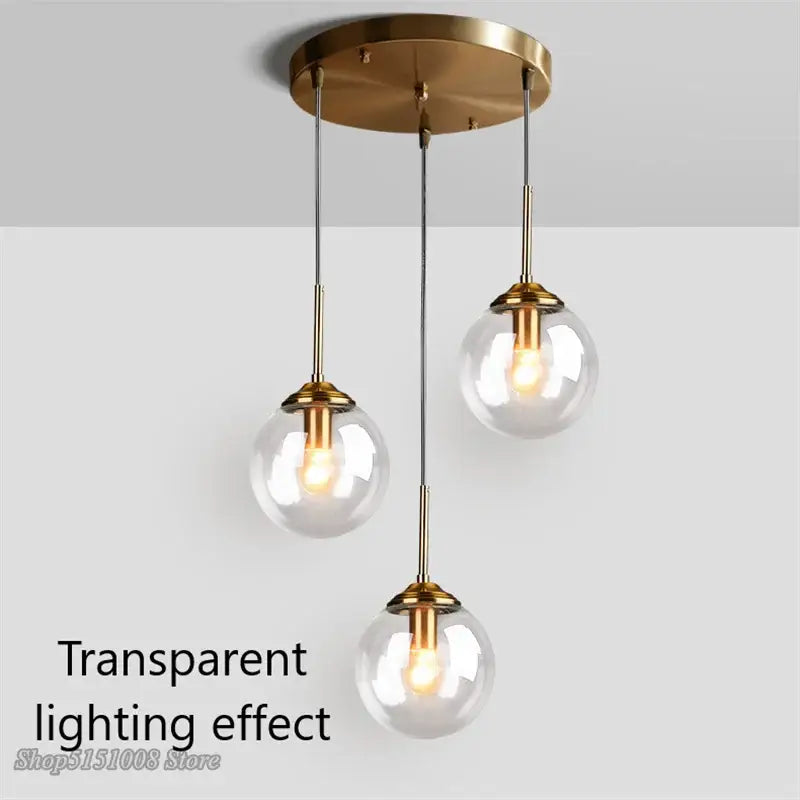 Brass-finished pendant lights with three clear glass pendant globe shades for kitchen and dining room use