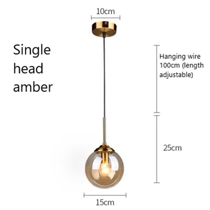 A single head modern brass and glass pendant light with an amber glass globe for kitchen and dining room use