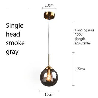 A sleek modern brass pendant light with a smoke gray glass pendant globe ideal for kitchen or dining room