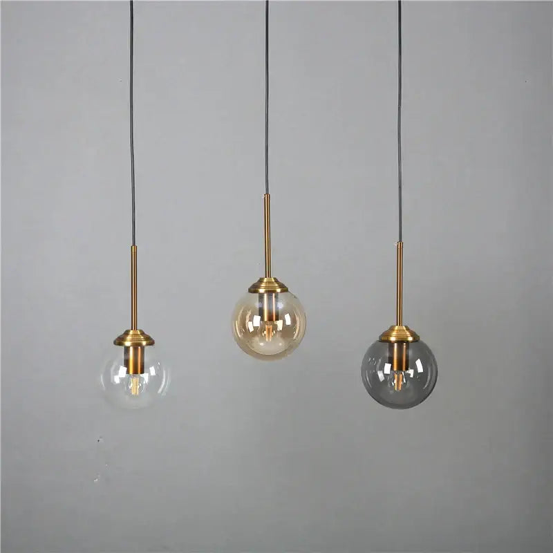 Modern brass and glass pendant lights with clear, amber, and smoked gray glass pendant shades for kitchen dining room