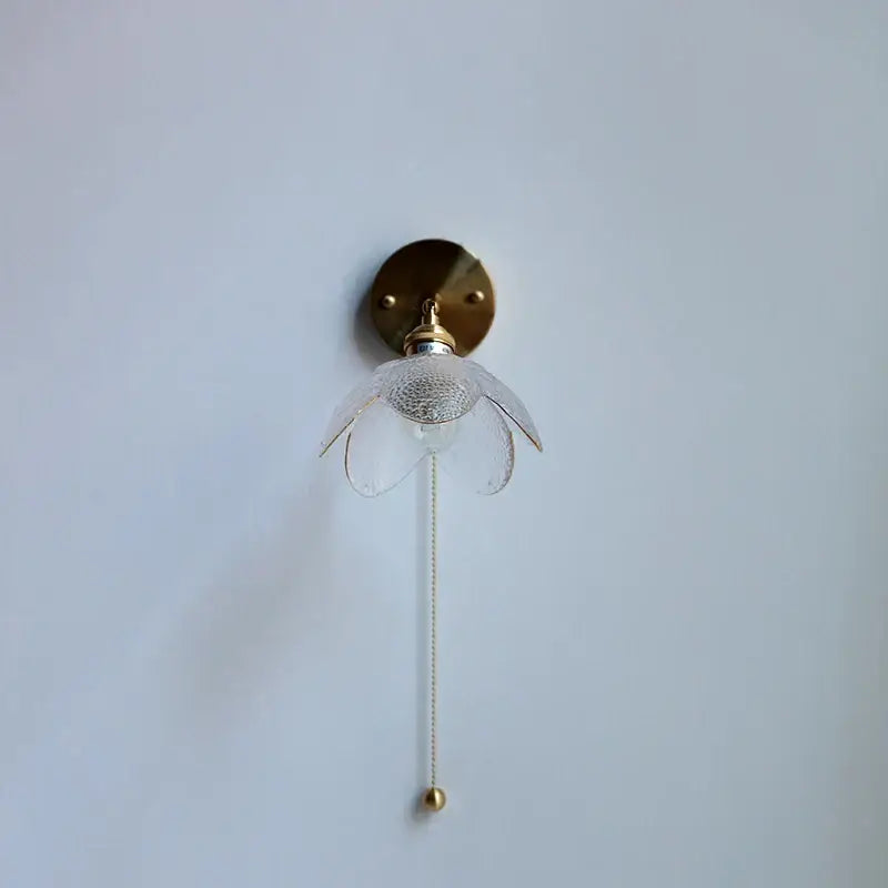 Modern brass and gray glass led wall sconce with delicate flower-shaped glass and pull chain for bedroom lighting