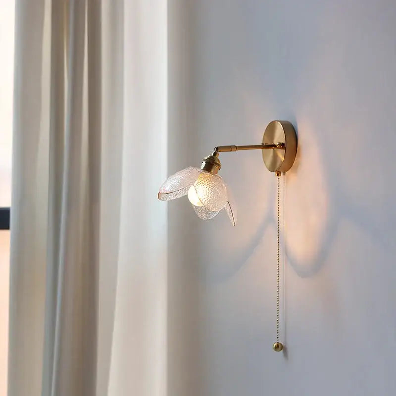 Modern brass and gray glass led wall sconce with textured flower shade and pull chain for bedroom lighting