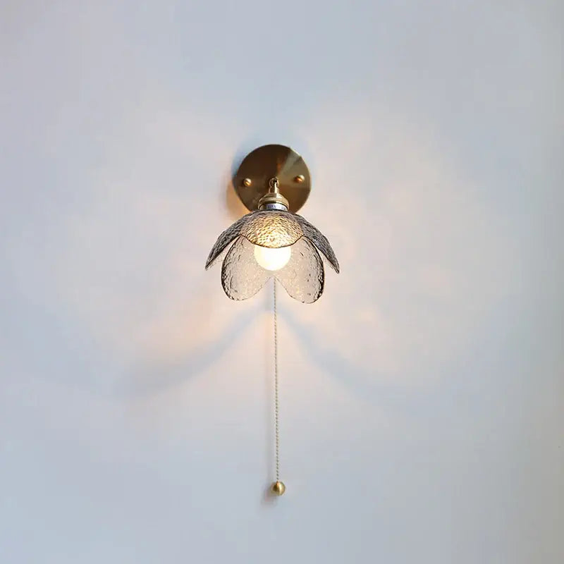 Modern brass and gray glass led wall sconce with textured flower shade and elegant pull chain for bedroom lighting