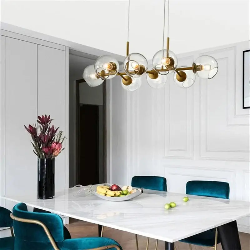 Modern brass pendant lights with gray glass globes suspended above a marble dining table for kitchen dining room