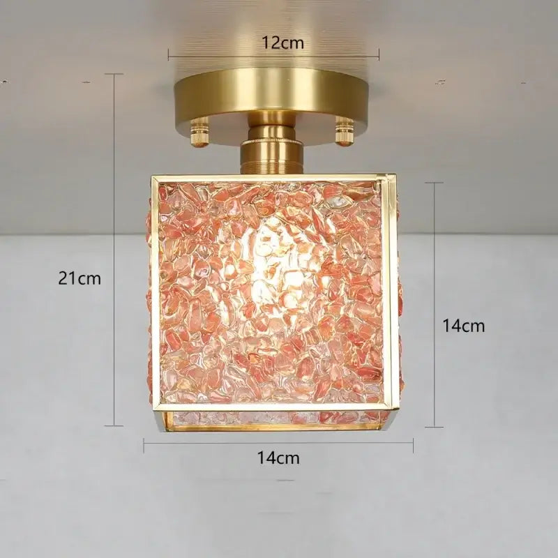 Modern brass ceiling light with a gold-toned metal frame and decorbites crystal glass panel filled with pinkish-orange stones
