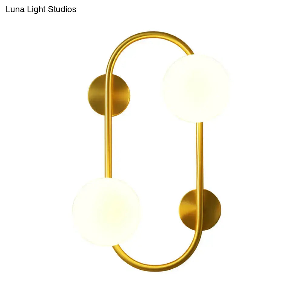 Modern brass and milk glass led wall mount lamp with gold-toned fixture and two frosted glass globes for bedroom use