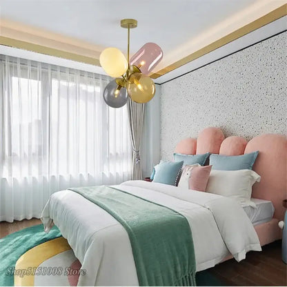 Modern brass pendant light featuring pastel-colored balloon-shaped glass pendant lights with gold-toned metal arms for dining room