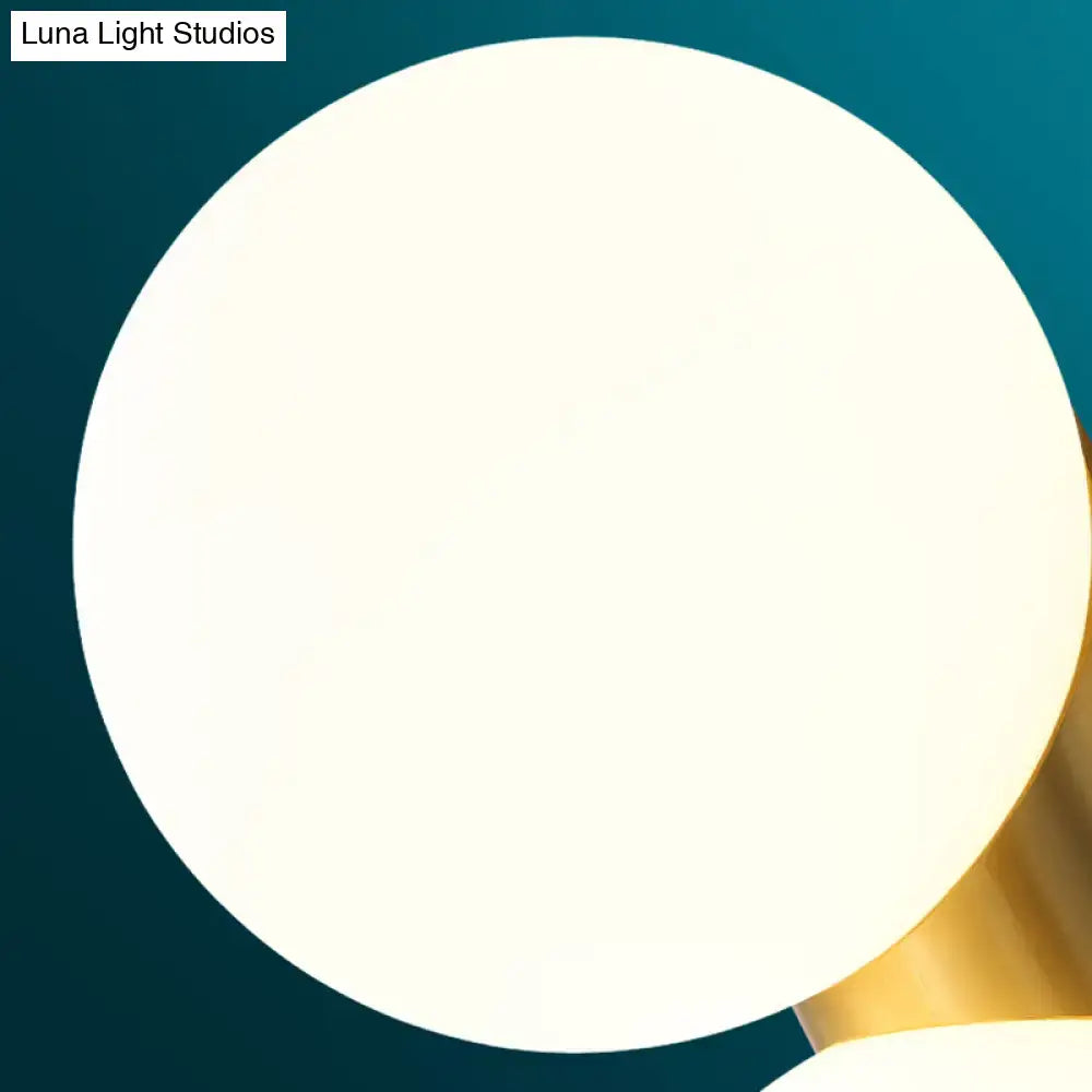Modern brass and opal glass wall mount lamp with a sleek white spherical shade and polished gold-toned metal base
