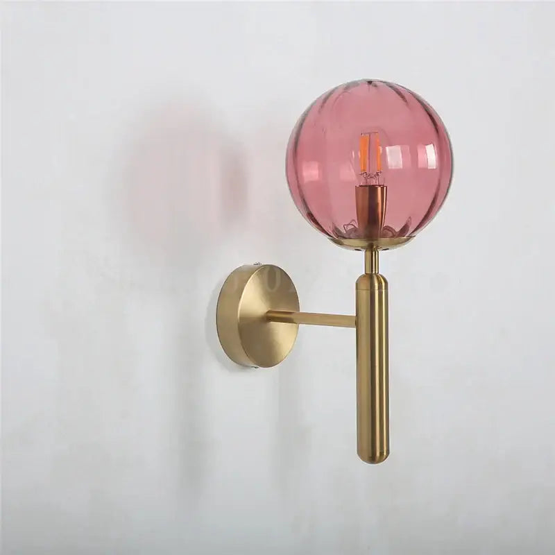 Modern brass and pink glass wall lamp with translucent ridged globe and exposed bulb for living room decorbites wall lamp